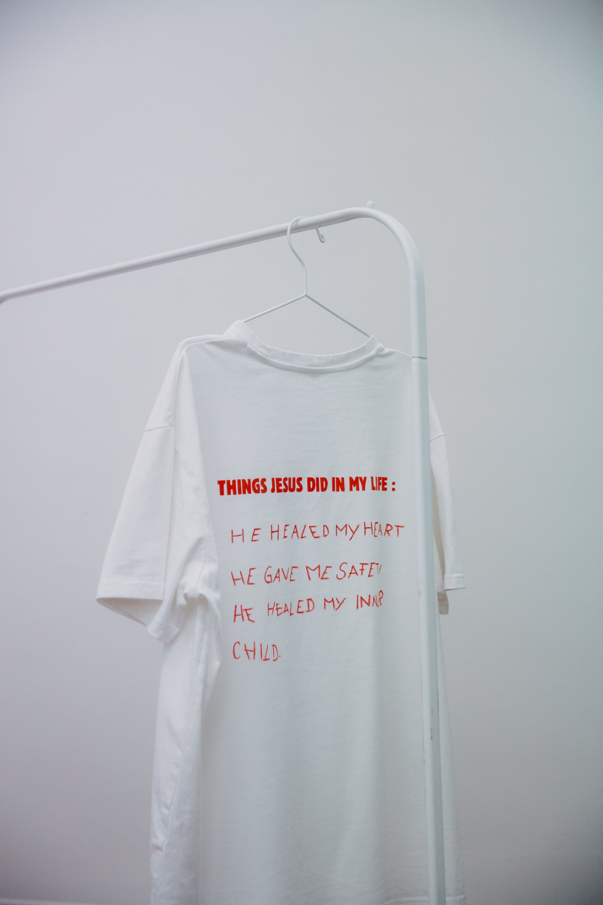 "Ein kreatives, selbstgestaltetes T-Shirt mit handgeschriebenen Botschaften , die den Glauben und persönliche Erfahrungen ausdrücken. Das T-Shirt ist mit einem Textilmarker beschriftet und zeigt inspirierende Zitate, die zur Gemeinschaft und zur Reflexion über den Glauben anregen."